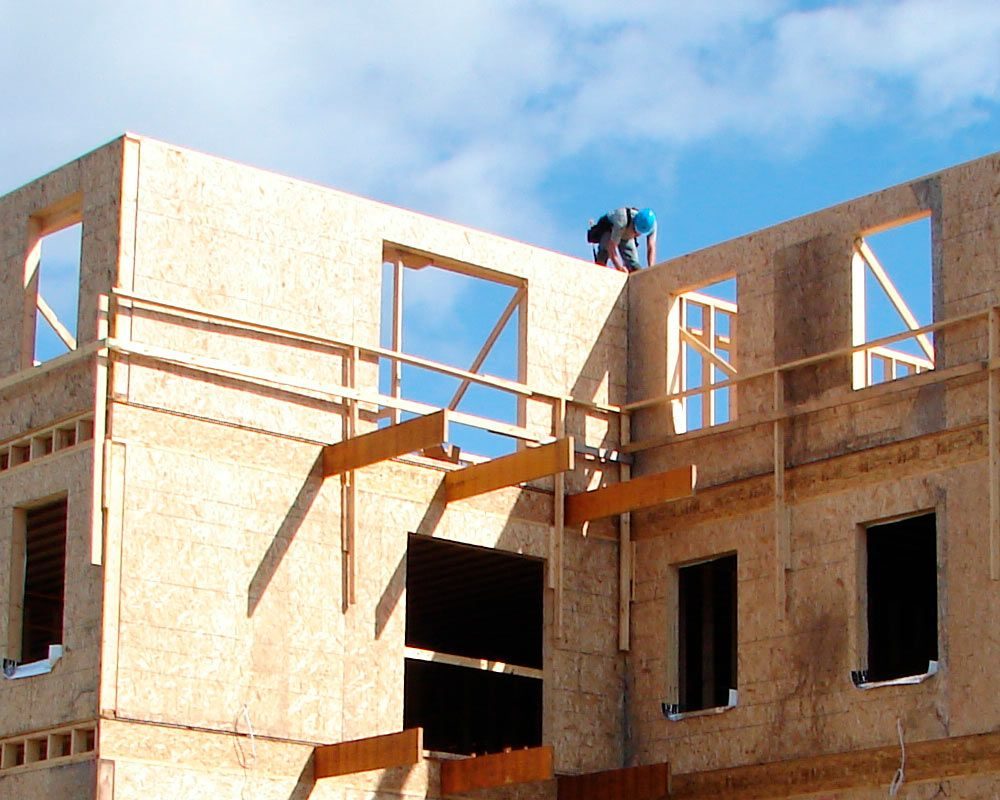 Deux travailleurs sur un montage de murs en panneaux, à l'étage d'un bâtiment en construction